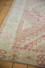 Distressed pile texture with dusty raspberry geometric and hook motifs on vintage Oushak rug.