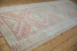 Distressed texture and dusty raspberry geometric floral motifs on vintage Oushak rug runner.