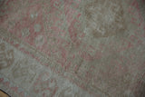 Distressed pile of vintage Oushak rug with faded dusty raspberry geometric design.