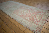 Distressed Oushak rug runner showing faded dusty raspberry and ivory geometric floral motifs.