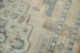 Distressed Oushak pile showcasing soft ivory, slate blue, and pale gold geometric floral motifs.