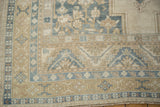 Distressed vintage Oushak carpet corner, showcasing stepped outlines, floral motifs in ivory, slate blue, pale gold.