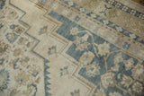 Distressed vintage Oushak rug's serrated outline and floral motifs in ivory, slate blue.