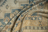Draped vintage Oushak rug detail, highlighting distressed pile, ivory, slate blue, and pale gold motifs.