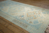 Powder blue and pale coffee brown germinating plant motifs on ivory distressed Oushak rug.