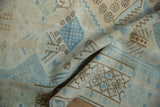 Folded vintage distressed Oushak carpet displaying powder blue and ivory geometric patterns.