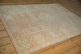 Distressed geometric patterns in terra cotta and seafoam green on a vintage Melas rug side.