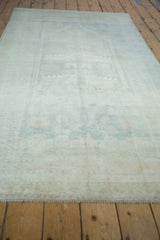 Distressed Oushak runner, its faded pile revealing subtle ivory and pale blue geometric leaves.