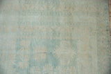 Distressed Oushak rug pile texture with even wear, muted blues, and ivory geometric motifs.