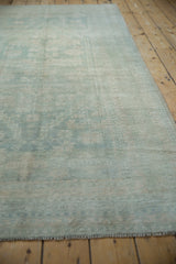 Distressed Oushak rug pile, showing even wear and faded pale blue and ivory tones.