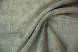Folds across distressed vintage Oushak rug showcase varied pale blue and ivory pile.