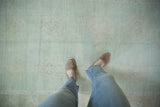 Close-up of the vintage distressed Oushak rug's seafoam green pile with faded floral patterns.