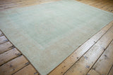 Distressed vintage Oushak rug, showing seafoam green abrashes, subtle border, and side selvage.