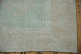Subtle floral pattern and distressed low pile in seafoam green and ivory of the Oushak rug.