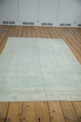 Vintage distressed Oushak rug in seafoam green and ivory, showing faded patterns and abrashes.