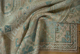 Distressed Melas rug texture, muted beige and blue, with worn pile and visible foundation.