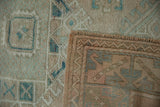 Distressed Melas rug's worn beige and blue pile, hand-knotted foundation, and intact selvage.