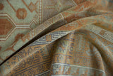 Distressed Oushak rug texture showing terracotta, sea foam, and navy geometric patterns.