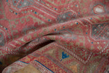 Folded Oushak runner showing distressed raspberry red, slate, and beige medallion patterns.