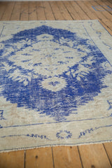 Heavily worn texture with vibrant cobalt blue floral motifs on the distressed vintage Oushak rug.