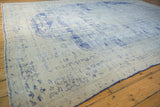 Distressed vintage Oushak carpet with worn cobalt blue patterns on an ivory ground.