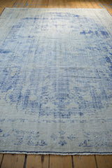Textured wear revealing cobalt blue and ivory knot heads on a distressed Oushak carpet.