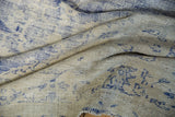 Close view of the distressed texture and faded cobalt blue patterns on a vintage Oushak carpet.