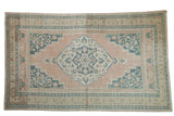 Distressed vintage Oushak rug with pale apricot field, dusty navy diamond medallion, and floral palmette borders.