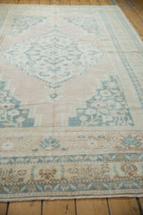 Vintage distressed Oushak rug: soft apricot field, dusty navy stepped medallion, and germinating plant borders.