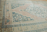 Distressed vintage Oushak rug corner showing apricot field, dusty navy palmettes, and vine borders.
