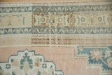 Pale apricot blush field, stepped medallion contour, dusty navy vine border, and short pile.