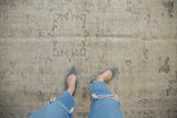 Distressed Oushak carpet texture with visible foundation and faded ivory floral vinery.