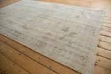 Distressed Oushak rug with faded floral patterns, worn pile, in ivory and pale blue.