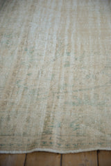 Distressed Oushak carpet texture with foundation showing through worn pile in seafoam green, ivory.