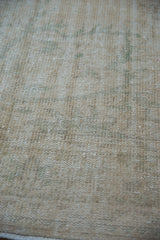 Worn pile of a distressed Oushak rug, showing ivory, cream, and faint seafoam green.