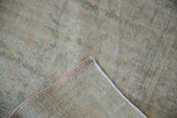 Distressed Oushak rug pile showing wear across knot heads and visible foundation, with intact selvage.