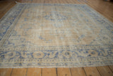 Angled view across the vintage Oushak carpet showing its low, distressed pile and texture.