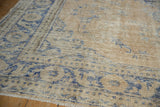 Distressed low-pile texture showing wear to the foundation of a sand and blue vintage Oushak carpet.