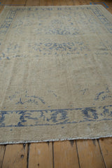 Distressed pile texture on a vintage Oushak rug, with softened ivory and cobalt blue patterns.