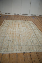 Distressed Oushak carpet corner showing wear to knot heads and muted book cover spandrel.