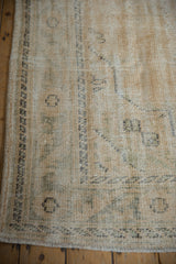 Distressed Oushak carpet showing worn texture, faded ivory and pale green motifs with fringe.
