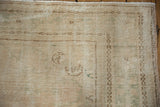 Distressed Oushak rug corner showing worn pile, coffee brown border motif, and intact selvage.