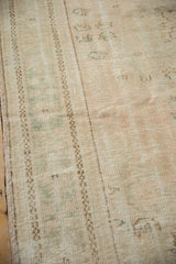 Distressed vintage Oushak rug pile featuring pale rose, green tones, and intact side selvage.