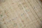 Distressed vintage Oushak carpet pile showing wear, with faded green and blue motifs.