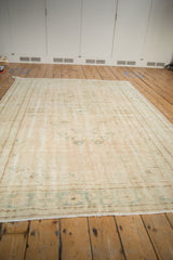 Distressed vintage Oushak rug, showing worn pale rose field and faded sea foam green floral motifs.