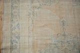 Distressed Oushak texture with faded beige field and dusty blue pattern detail.