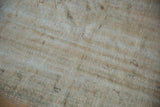 Distressed vintage Oushak carpet texture with worn pile exposing cream and brown foundation.