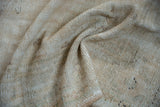 Textured cream and beige distressed Oushak pile, showing wear to foundation and knot heads.