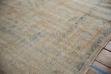 Faded cream and muted blue patterns on the distressed Oushak carpet pile.