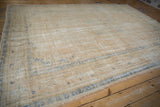 Distressed Oushak rug corner, worn cream-sand pile and subtle blue border pattern.
